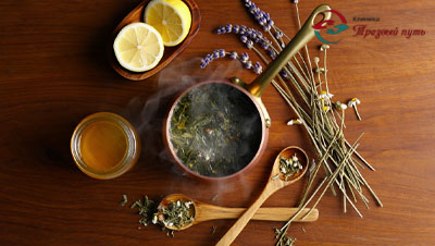 Отвар травы в кастрюльке на столе, рядом трав и лимон